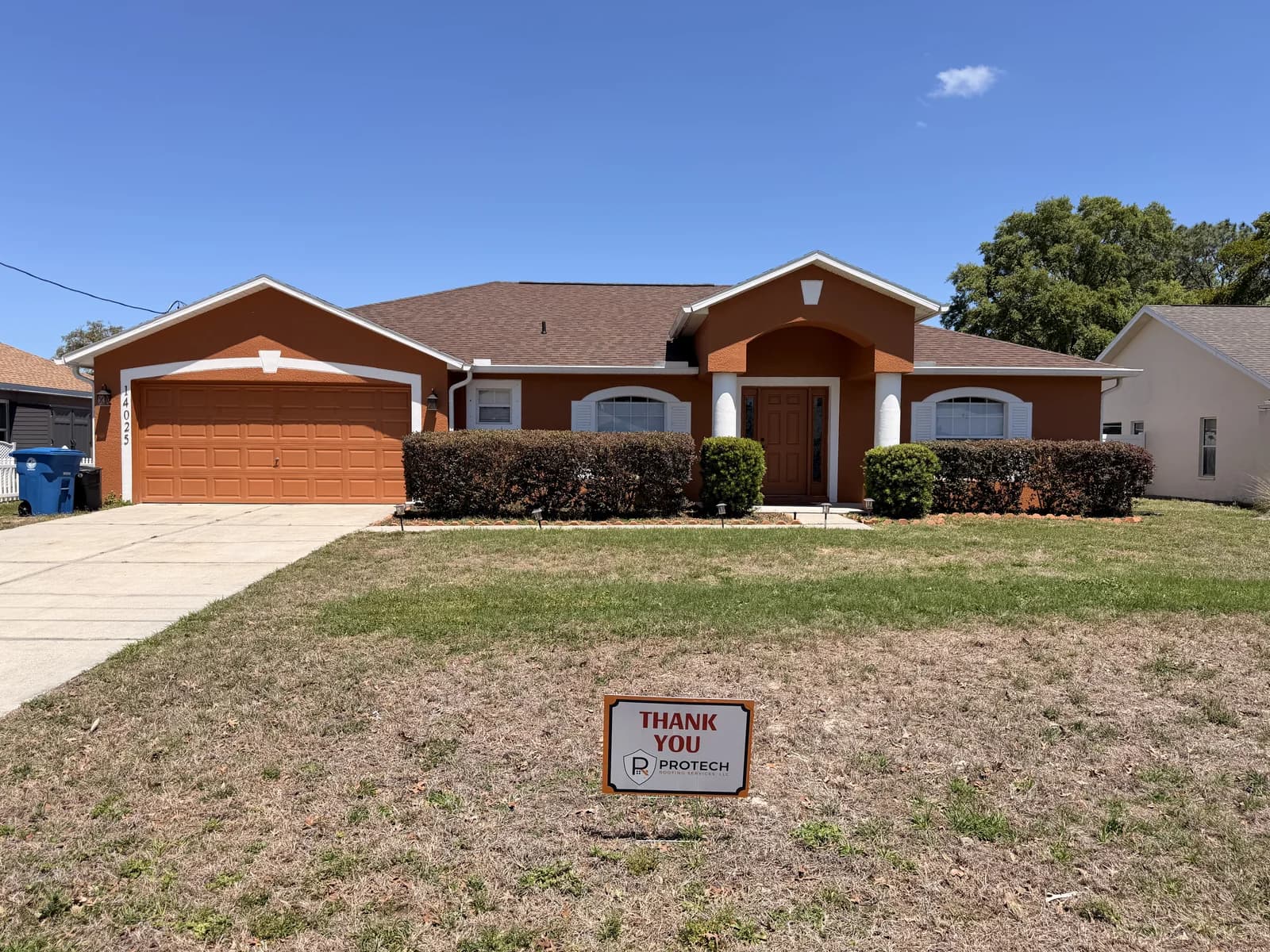 New architectural shingle roof on a terracotta stucco Hernando County home, with a Protech Roofing thank-you yard sign on the front lawn